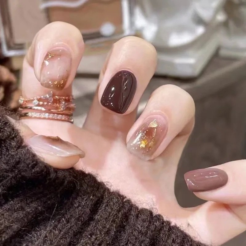 Uñas press on marrón con diseños dorados